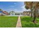 Private backyard with a pergola, a swimming pool, sliding glass doors, tropical palm trees, and lush grass at 4099 Pompano Se Dr, St Petersburg, FL 33705
