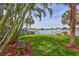 Backyard view showcasing lawn, tropical trees, and canal at 4099 Pompano Se Dr, St Petersburg, FL 33705