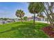 Landscaped backyard featuring a dock, pool, a grassy area with palm trees, and a fenced perimeter at 4099 Pompano Se Dr, St Petersburg, FL 33705