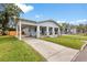 Charming light blue bungalow featuring a covered front porch, verdant lawn, and a convenient covered driveway at 419 W Osborne Ave, Tampa, FL 33603