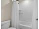 Bright bathroom with a white tiled shower and a matching white shower curtain, toilet, and tub at 4345 Cadence Loop, Land O Lakes, FL 34638