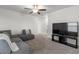 Relaxing living room with gray sectional sofa, plush carpeting, modern ceiling fan, and large TV at 4345 Cadence Loop, Land O Lakes, FL 34638