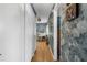 Hallway with hardwood floors and stylish wallpaper leading to a room with a white piano and ample natural light at 4499 Collins Rd, Spring Hill, FL 34606