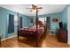 Main bedroom featuring blue walls, wood flooring, four-poster bed and two windows at 4499 Collins Rd, Spring Hill, FL 34606
