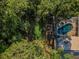 Aerial view of a private backyard with a screened pool, spa, and custom fire pit surrounded by trees at 4962 Turtle Creek Trl, Oldsmar, FL 34677
