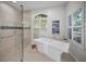 Bright bathroom features a modern soaking tub next to the walk-in shower and window at 4962 Turtle Creek Trl, Oldsmar, FL 34677