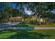 Well-maintained front yard with mature trees, lush landscaping, and a three-car garage at 4962 Turtle Creek Trl, Oldsmar, FL 34677