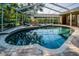 Beautiful backyard pool with a screened enclosure, lush landscaping, and lounge chairs, perfect for relaxation at 4962 Turtle Creek Trl, Oldsmar, FL 34677