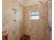 Walk-in shower featuring travertine tile, a shower bench and a window for natural light at 510 33Rd N Ave, St Petersburg, FL 33704