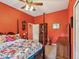 Cozy bedroom with orange walls, wood furniture and a floral comforter at 5100 Lockhart Rd, Brooksville, FL 34602