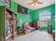 A quirky bedroom with green walls, filled with memorabilia, a bookshelf, and a large window with natural light at 5100 Lockhart Rd, Brooksville, FL 34602