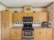 Charming kitchen with wood cabinets, floral wallpaper, and stainless steel appliances at 5100 Lockhart Rd, Brooksville, FL 34602