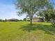 Expansive yard with lush green grass, mature trees, and a home featuring a screened-in pool area at 5100 Lockhart Rd, Brooksville, FL 34602