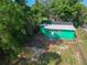Rear view of a single Gathering home featuring green paint and a backyard surrounded by lush greenery at 5510 12Th St, Zephyrhills, FL 33542