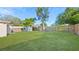 A large grassy backyard featuring a wood fence for privacy and mature trees at 6334 Hyperion Dr, Port Richey, FL 34668