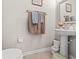 Cozy half-bathroom with a pedestal sink, decorative mirror, and convenient towel rack at 6974 Holly Heath Dr, Riverview, FL 33578