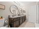 Bathroom boasts a granite-topped double vanity with round mirrors and updated lighting fixtures at 6974 Holly Heath Dr, Riverview, FL 33578
