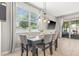A dining room features a dark wood table, four gray chairs, a window, and an overhead light fixture at 6974 Holly Heath Dr, Riverview, FL 33578