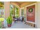 Cozy front porch with seating area, decorative wreath on the door, and charming 'Welcome' sign at 6974 Holly Heath Dr, Riverview, FL 33578
