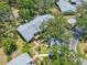 An aerial view of a home with a gray roof surrounded by trees and lush landscaping and a nearby parking area at 70 Cypress Pl, Oldsmar, FL 34677