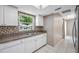 Galley kitchen featuring white cabinetry, stainless steel sink and faucet, and a tiled backsplash at 70 Cypress Pl, Oldsmar, FL 34677