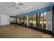 Sunroom with many windows showing a well-manicured lawn, carpeting, and ceiling fans at 70 Cypress Pl, Oldsmar, FL 34677