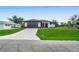 Modern single-story home featuring a two-car garage, a well-manicured lawn, and a brick-paved driveway at 7054 Rosemont Dr, Englewood, FL 34224