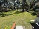 Large backyard with mature trees, green grass, and a glimpse of the home's exterior at 708 Keeling St, Brooksville, FL 34601