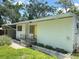 Side exterior of the home featuring a yellow door and landscaped garden beds at 708 Keeling St, Brooksville, FL 34601