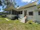 Home exterior featuring a screened porch, wood trim, an air conditioner, and a small yard at 708 Keeling St, Brooksville, FL 34601