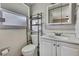 Cozy bathroom featuring white tile walls, toilet, storage shelf, and vanity with a large mirror at 7810 Pineapple Ln, Port Richey, FL 34668