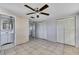 Bedroom view showing tile floors, a ceiling fan, and access to both the bathroom and closets at 7810 Pineapple Ln, Port Richey, FL 34668