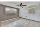 Neutral bedroom with tile flooring, two windows, and a ceiling fan at 7810 Pineapple Ln, Port Richey, FL 34668