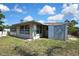 Rear view of the home featuring an attached storage unit and lush grass at 7810 Pineapple Ln, Port Richey, FL 34668