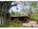 Charming home exterior with a screened patio, colorful landscaping, and a tree with vines at 8260 32Nd N Ave, St Petersburg, FL 33710