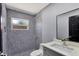 Bathroom with patterned tile shower, gray vanity, and large mirror; modern design at 8603 N 9Th St, Tampa, FL 33604