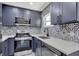 Gray kitchen cabinets with white countertop, stainless steel appliances and patterned tile backsplash at 8603 N 9Th St, Tampa, FL 33604
