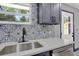 Kitchen with stainless sink, patterned backsplash, white countertop, and dark grey cabinets at 8603 N 9Th St, Tampa, FL 33604