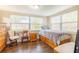 Bright bedroom with hardwood floors, a bed, two chairs, and plenty of natural light from two windows at 9020 Gray Fox Ln, Port Richey, FL 34668