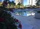 Community pool area with lounge chairs and yellow umbrellas surrounded by tropical landscaping at 100 1St N Ave # 702, St Petersburg, FL 33701