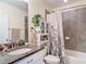 Bright bathroom featuring granite counters, decorative shower curtain and tiled bath surround at 1022 Montgomery Bell Rd, Wesley Chapel, FL 33543