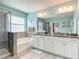Large bathroom featuring double vanity, tub, walk-in shower and light turquoise-colored walls at 1022 Montgomery Bell Rd, Wesley Chapel, FL 33543