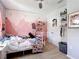 Whimsical bedroom featuring playful pink wall art, cozy decor, and comfortable carpeting at 1022 Montgomery Bell Rd, Wesley Chapel, FL 33543