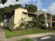 Exterior shot of a condo building with beautifully landscaped yard featuring a variety of plants and flowers at 1100 E Bay Dr # 96, Largo, FL 33770