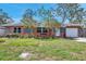 Charming single-story home with a well-manicured lawn, colorful flowers, and a cozy bench in front at 11348 59Th Ter, Seminole, FL 33772