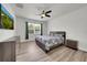 Cozy bedroom featuring a ceiling fan, window view, and wood laminate flooring at 1203 Custer Bayou Street, Ruskin, FL 33570