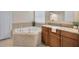 Bright bathroom with a corner bathtub, mosaic tile accents, and wood cabinets with granite countertops at 1229 Hillandale Reserve Dr, Tampa, FL 33613