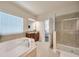 Bright bathroom includes a glass enclosed shower, soaking tub, and wood cabinets with granite countertops at 1229 Hillandale Reserve Dr, Tampa, FL 33613