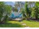 Relax and unwind in this backyard space featuring lush foliage surrounding Adirondack chairs on a small wooden deck at 1263 Overcash Dr, Dunedin, FL 34698