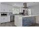 Modern kitchen with white cabinetry, a stainless steel refrigerator, a stylish backsplash, and a large center island at 1263 Overcash Dr, Dunedin, FL 34698